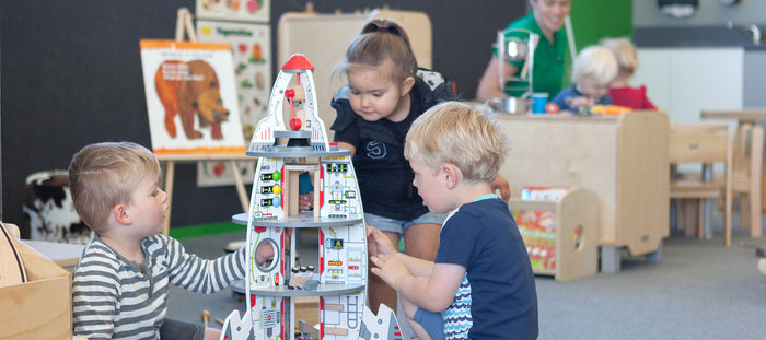 3 preschoolers playing with a rocket ship at A pot full of colourful felt tip pens at Tadpoles Early Childhood Centre