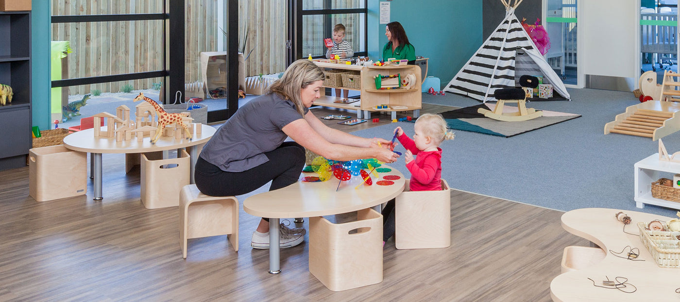 Teacher and toddler playing at a table at A pot full of colourful felt tip pens at Tadpoles Early Childhood Centre