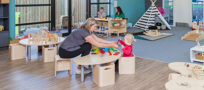 Teacher and toddler playing at a table at A pot full of colourful felt tip pens at Tadpoles Early Childhood Centre
