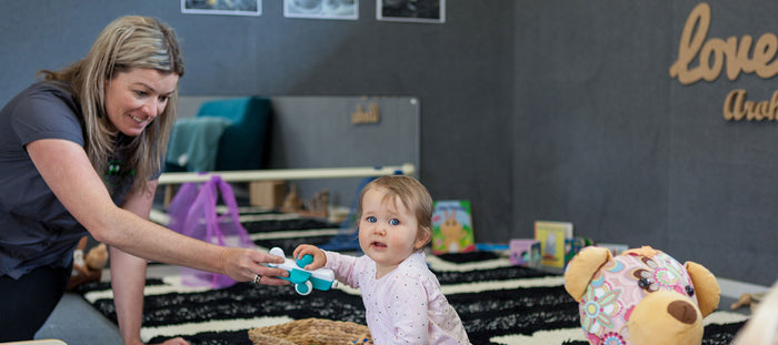 A teacher and baby girl playing at A pot full of colourful felt tip pens at Tadpoles Early Childhood Centre