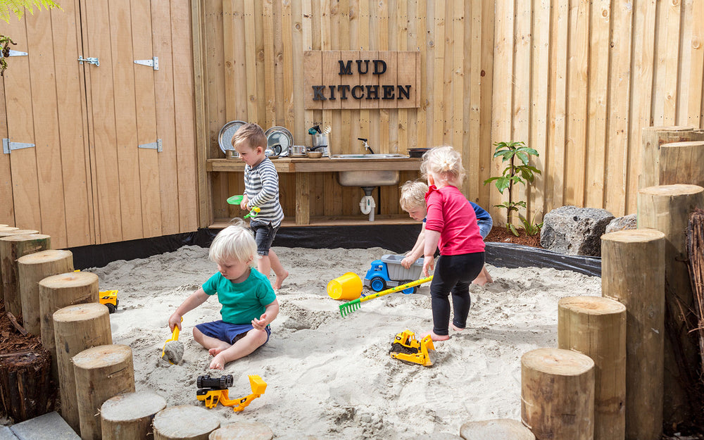 4 kids playing with toys in a sandpit at A pot full of colourful felt tip pens at Tadpoles Early Childhood Centre