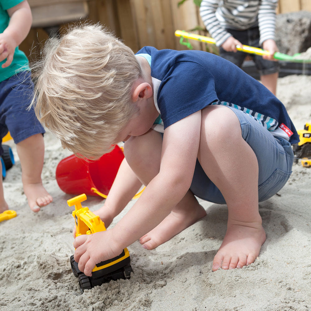 A little boy playing with a yellow digger in a sandpit at A pot full of colourful felt tip pens at Tadpoles Early Childhood Centre